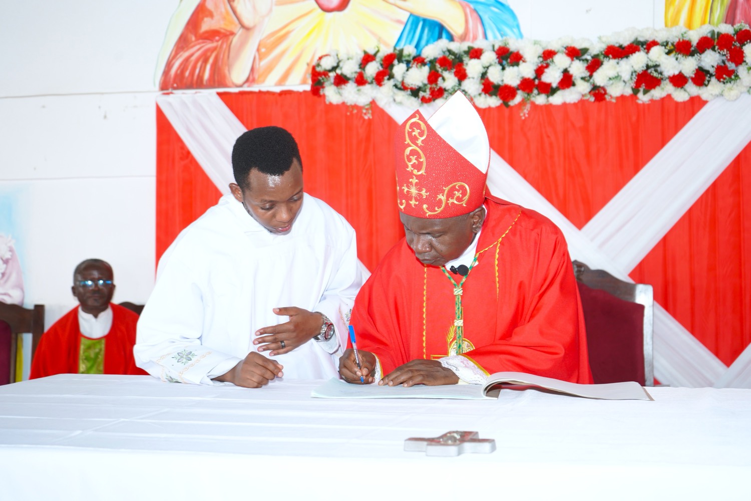 Signing a copy beside the bishop, in full vestments.